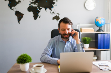 Business owner setting up a remote team on a laptop with a world map in background